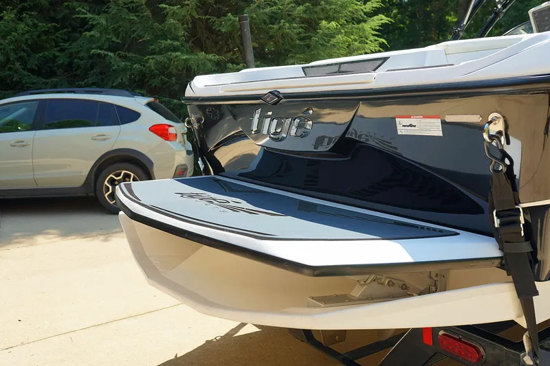 Slide: The Image of 2014 Tigé R20 boat rear view with swim platform, parked near a car. - 36