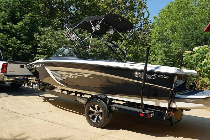Slide: The Image of 2014 Tigé R20 boat on trailer, parked in driveway, surrounded by trees. - 37