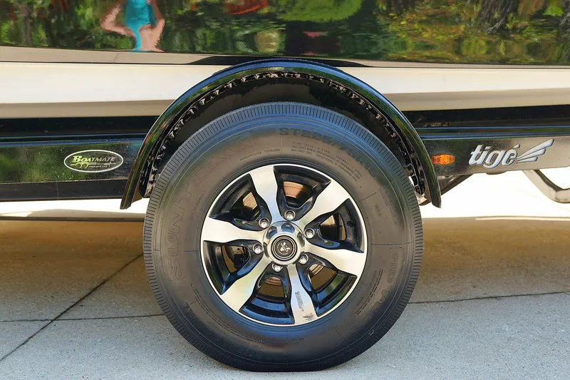 Slide: The Image of 2014 Tigé R20 boat trailer wheel with chrome rim on pavement. - 44