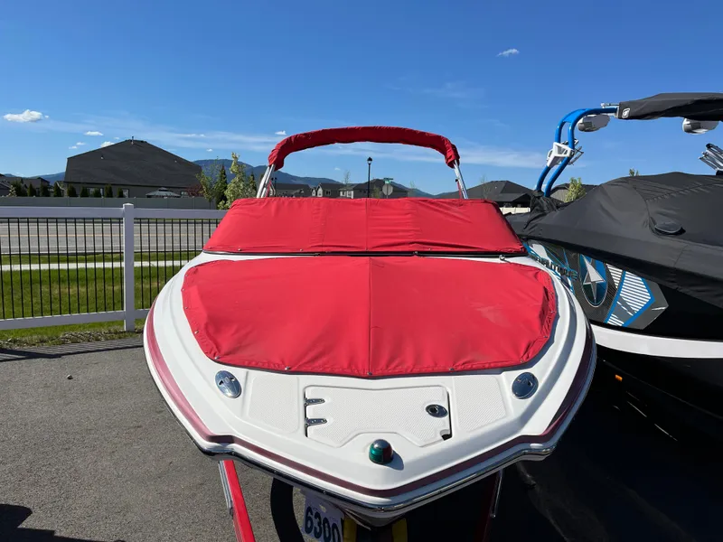 Slide: The Image of 2012 Chaparral 216 SSi boat with red cover, parked outdoors on a sunny day. - 17