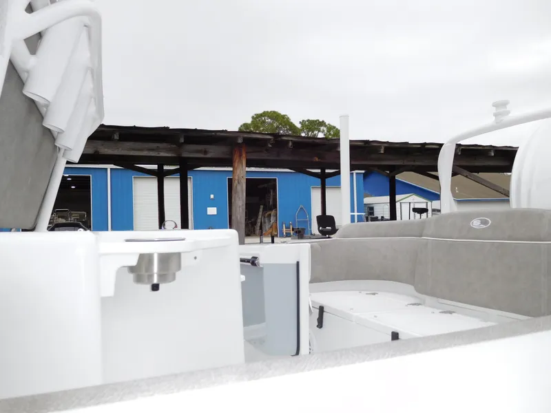 Slide: The Image of 2025 Sea Hunt Ultra 239 SE boat interior at a marina with blue storage buildings. - 3