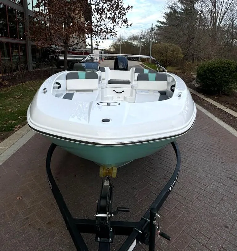 Slide: The Image of 2025 Tahoe T18 boat on trailer, parked on a brick path, surrounded by trees. - 2