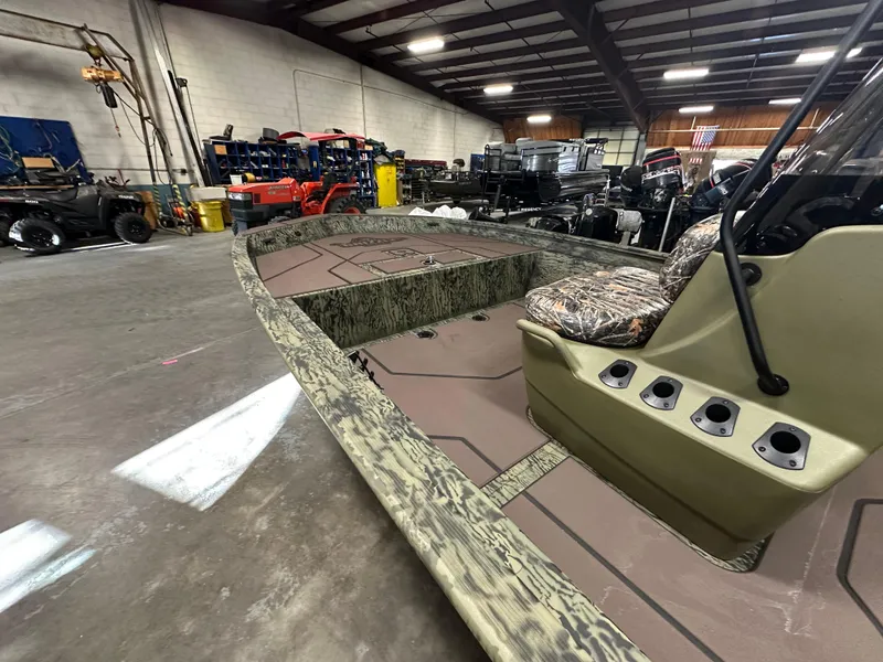Slide: The Image of 2025 Tracker Grizzly 1860 CC boat in a warehouse, featuring camo design and spacious interior. - 11