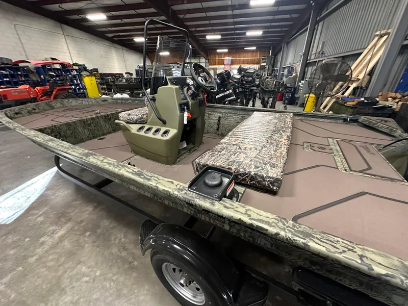 Slide: The Image of 2025 Tracker Grizzly 1860 CC boat in a warehouse, showcasing interior and steering console. - 12