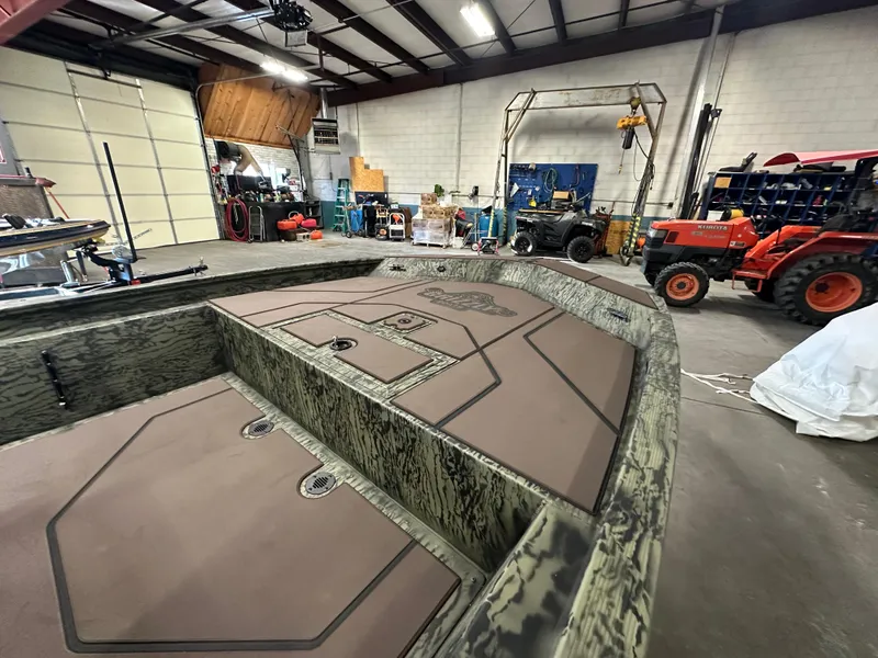 Slide: The Image of 2025 Tracker Grizzly 1860 CC boat in a workshop with equipment and tractor. - 5