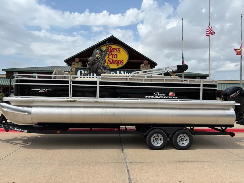 The Image of 2025 Sun Tracker Sportfish 24 XP3 pontoon boat on trailer, parked outdoors. - 0