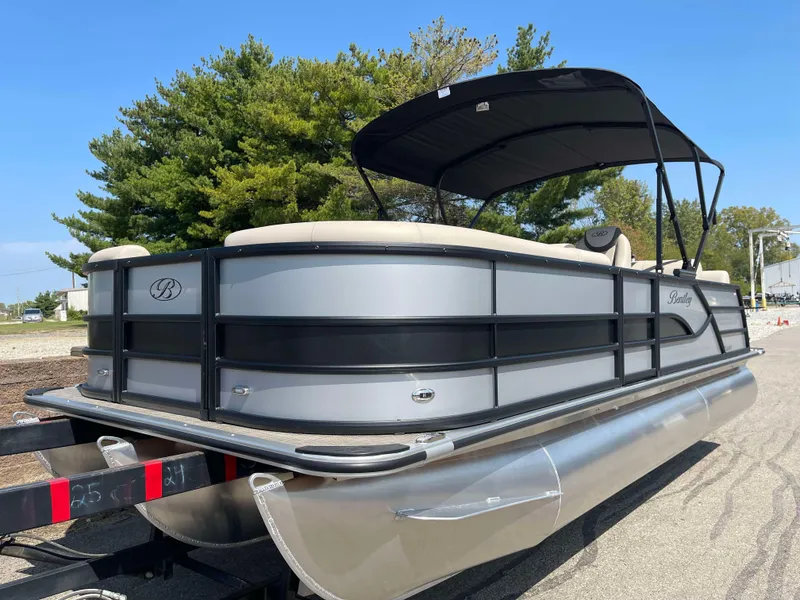 The Image of 2025 Bentley Pontoons Legacy 223 QSB, sleek design, black canopy, parked on trailer. - 0