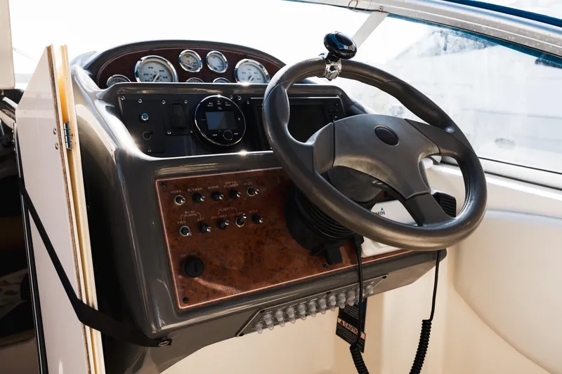 Slide: The Image of 2005 Bayliner 285 boat dashboard with steering wheel and control panel. - 12