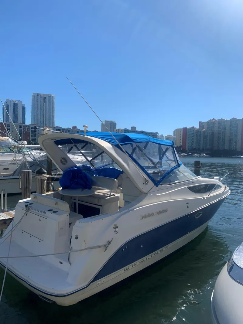Slide: The Image of 2005 Bayliner 285 boat docked in sunny marina with city skyline. - 20