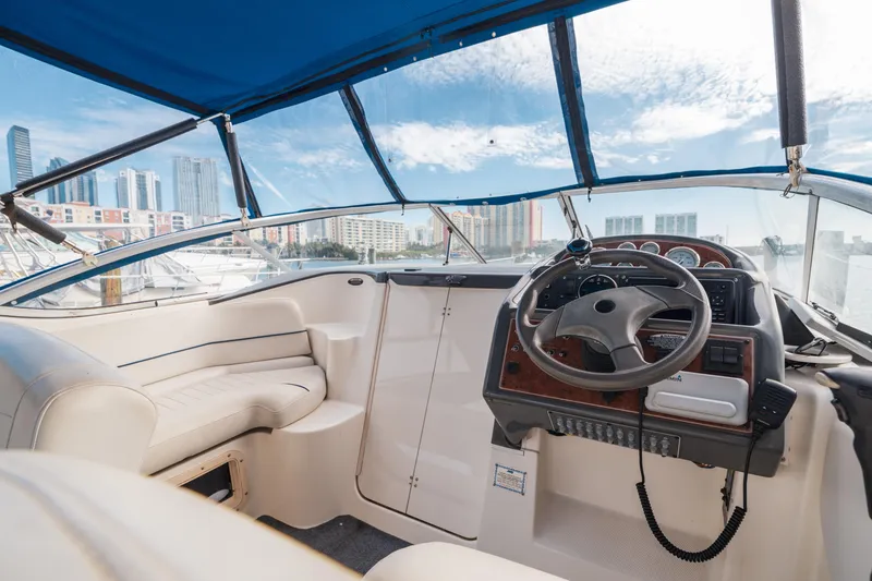 Slide: The Image of 2005 Bayliner 285 boat interior with steering wheel and seating, docked in a marina. - 6