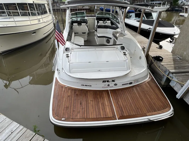 Slide: The Image of 2016 Sea Ray 350 SLX boat docked with wooden deck and American flag. - 1