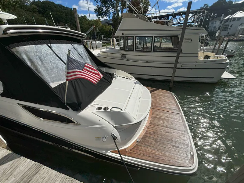 Slide: The Image of 2016 Sea Ray 350 SLX docked with American flag, sunny marina setting. - 12