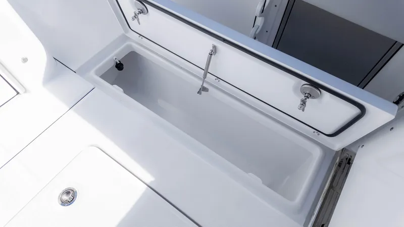 Slide: The Image of 2025 Everglades 315 Center Console storage compartment, open lid, white interior. - 15