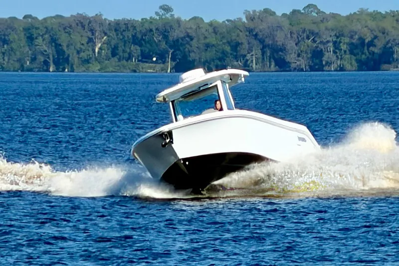 Slide: The Image of 2025 Everglades 315 Center Console boat cruising on a lake with forested background. - 39