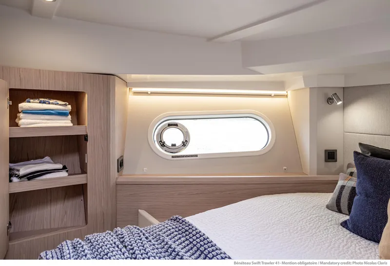 Slide: The Image of Interior of 2024 Beneteau Swift Trawler 41, featuring cozy bedroom with window and shelving. - 25