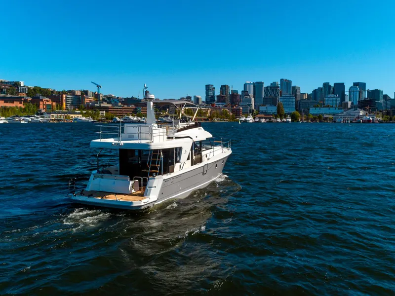 Slide: The Image of 2024 Beneteau Swift Trawler 41 cruising on a sunny day with city skyline backdrop. - 3