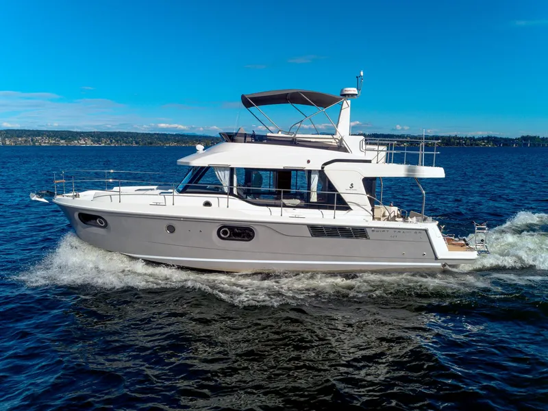 The Image of 2024 Beneteau Swift Trawler 41 cruising on open water under clear blue skies. - 0