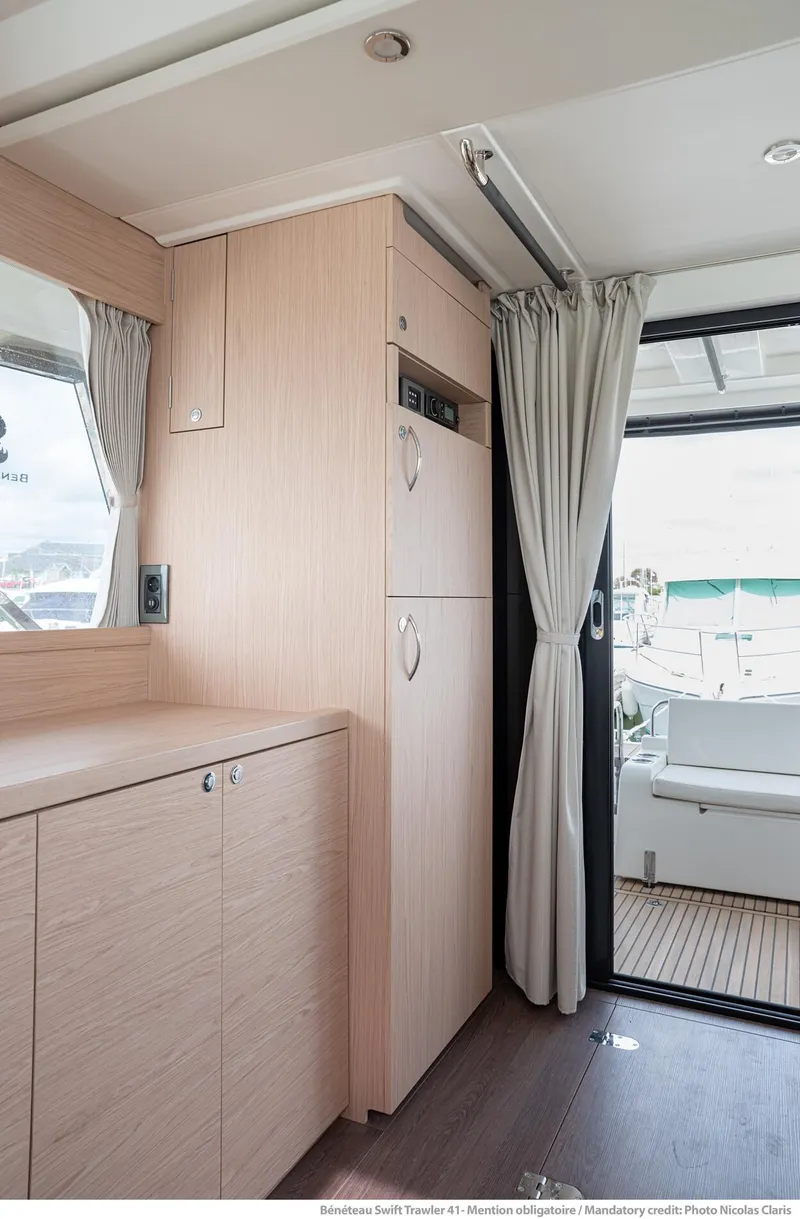Slide: The Image of 2024 Beneteau Swift Trawler 41 interior with light wood finish and outdoor view. - 18