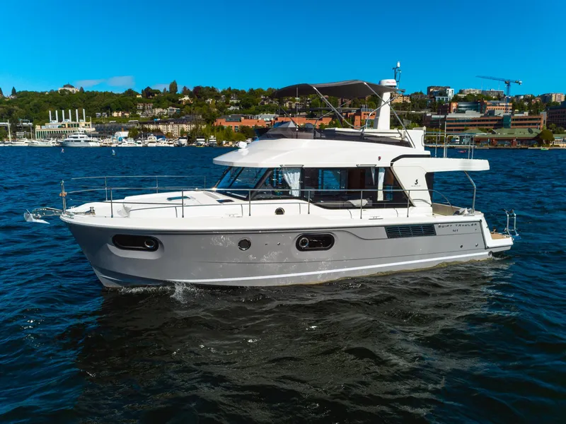 Slide: The Image of 2024 Beneteau Swift Trawler 41 cruising on a scenic waterfront. - 2
