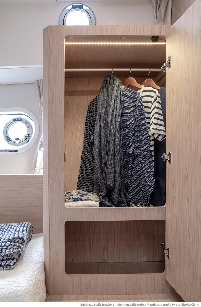 Slide: The Image of 2024 Beneteau Swift Trawler 41 cabin closet with clothes and porthole view. - 26