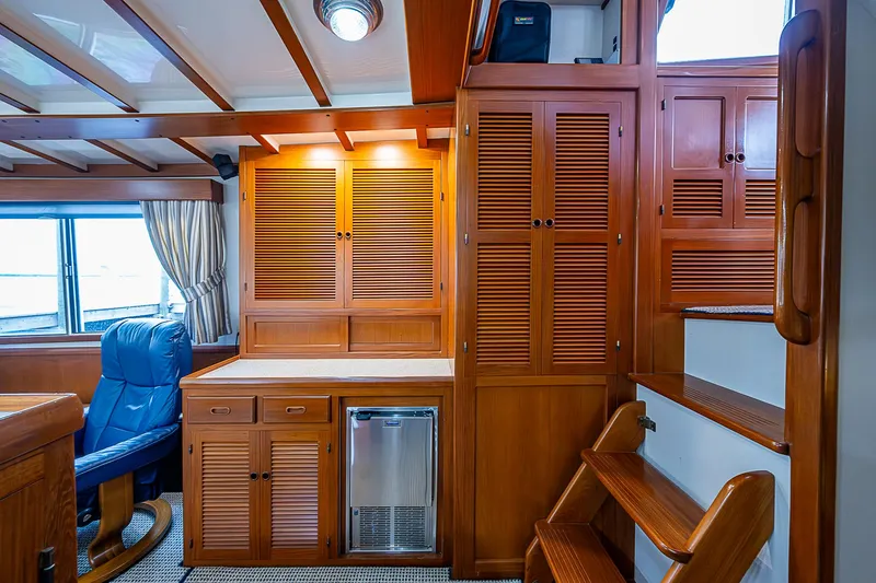 Slide: The Image of 2004 Kadey-Krogen North Sea interior with wooden cabinetry, blue chair, and stairs. - 11