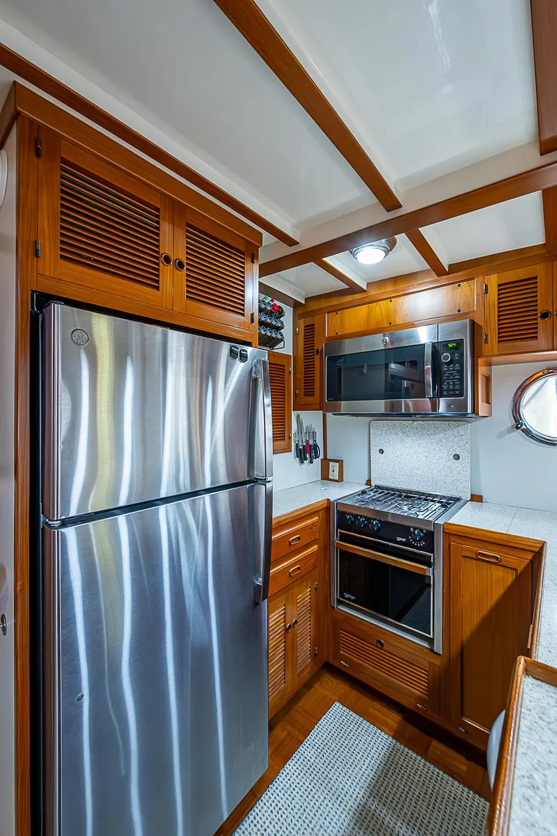 Slide: The Image of 2004 Kadey-Krogen Krogen North Sea yacht kitchen with stainless steel appliances and wooden cabinetry. - 14