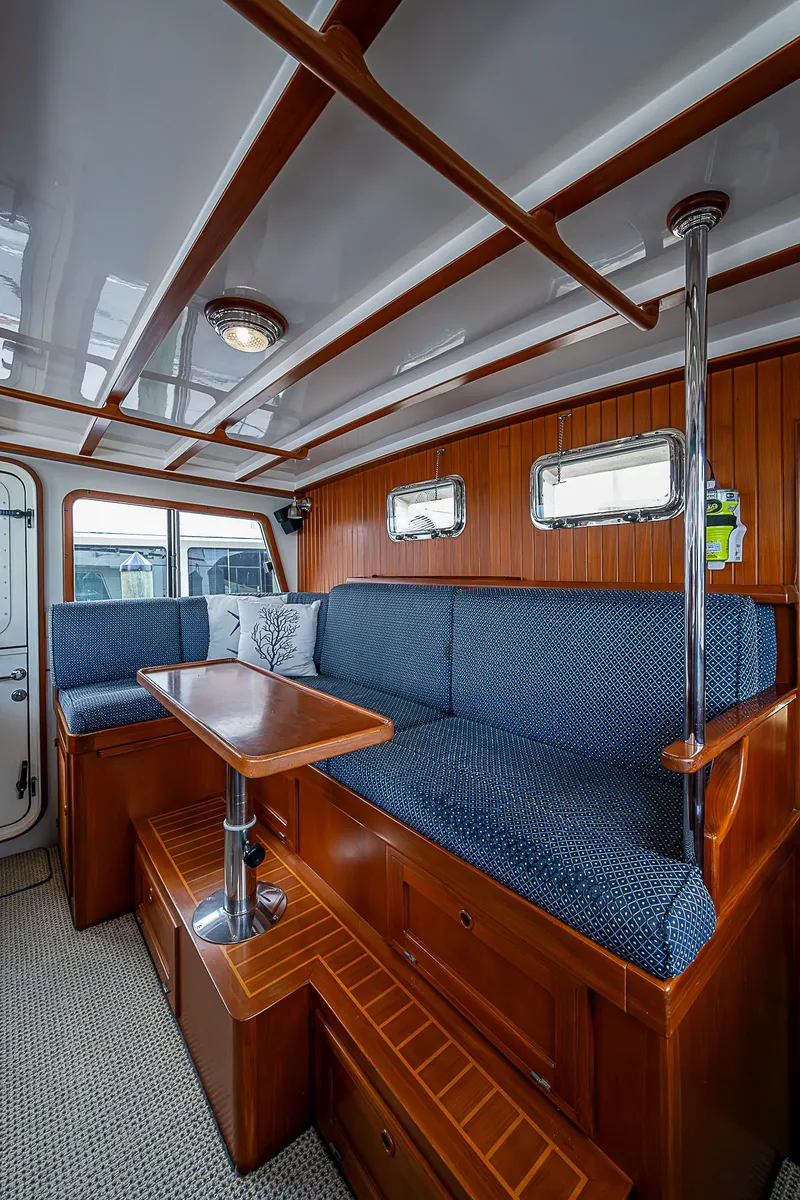 Slide: The Image of 2004 Kadey-Krogen North Sea interior with blue seating, wooden accents, and a compact dining area. - 30