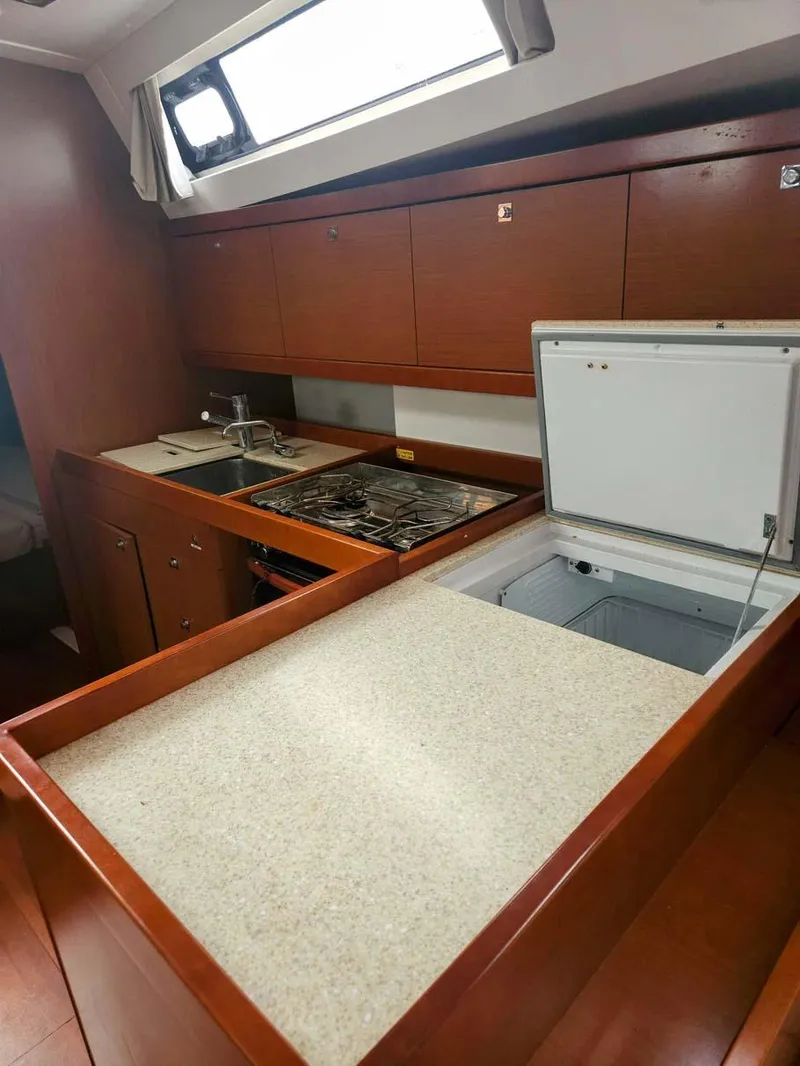 Slide: The Image of 2012 Beneteau Oceanis 41 yacht kitchen with wood cabinetry and modern appliances. - 22