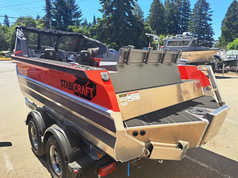 Slide: The Image of 2024 Stabicraft Treker Profish boat, red and silver, parked outdoors. - 2