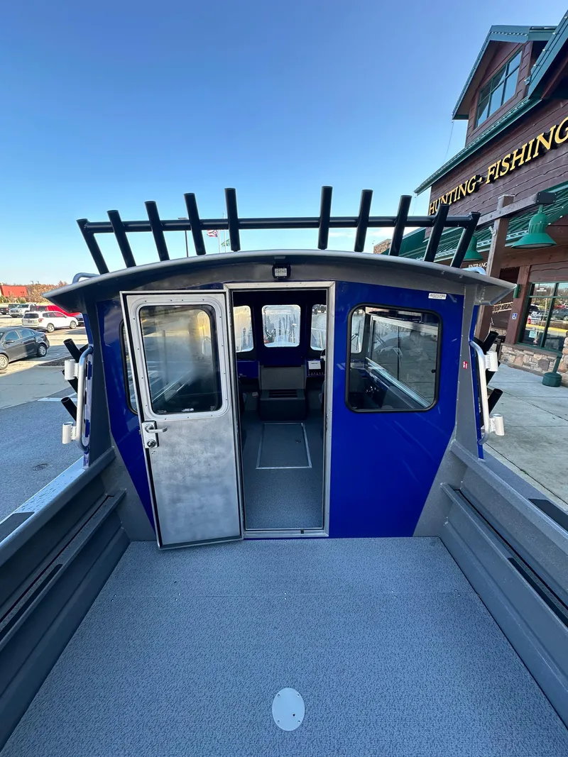 Slide: The Image of 2025 Spartan 240 Maximus Pro boat, blue exterior, parked near a fishing store. - 10