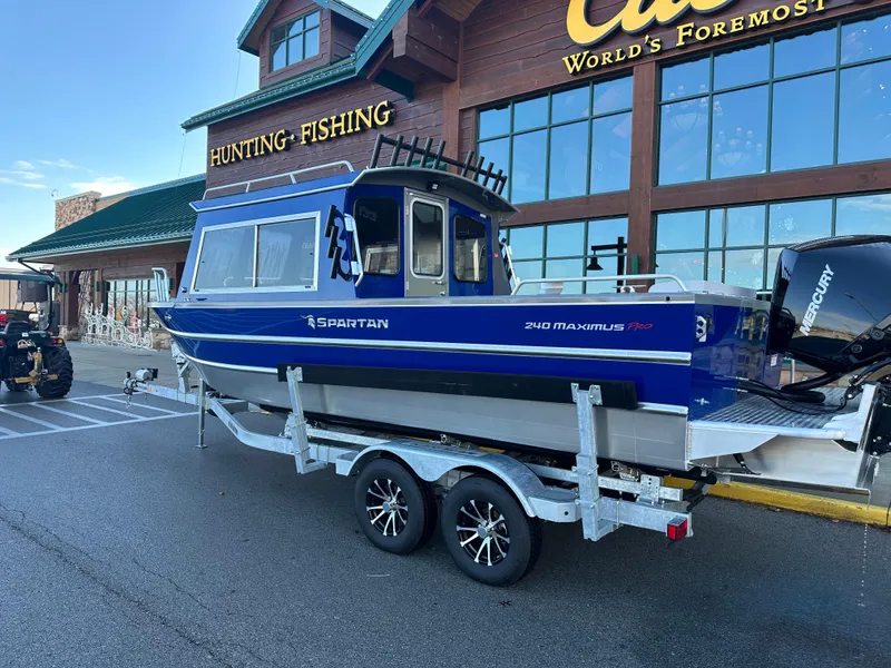 Slide: The Image of 2025 Spartan 240 Maximus Pro boat on trailer outside hunting and fishing store. - 6