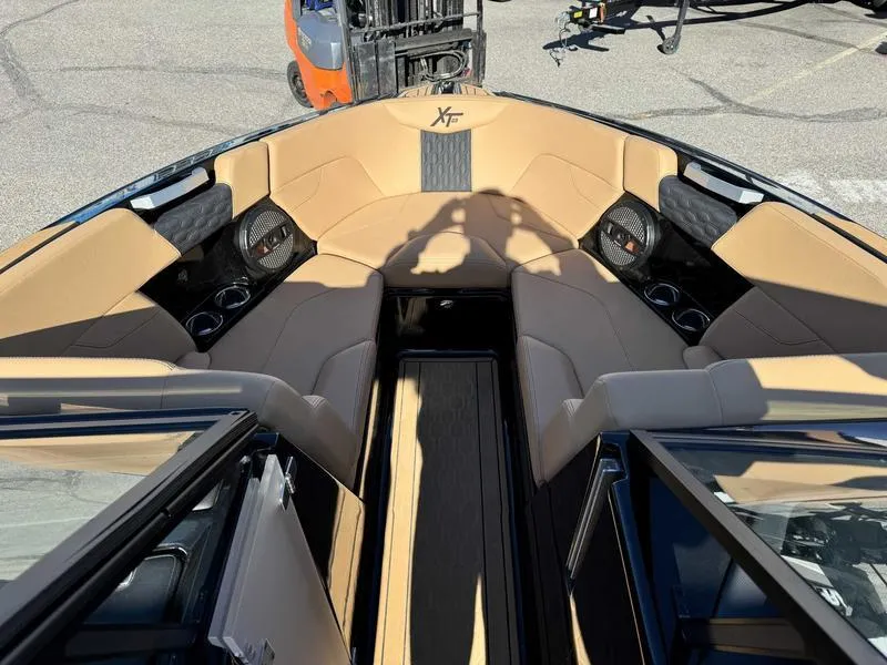 Slide: The Image of 2024 MasterCraft XT23 boat interior with tan seating and cup holders. - 12