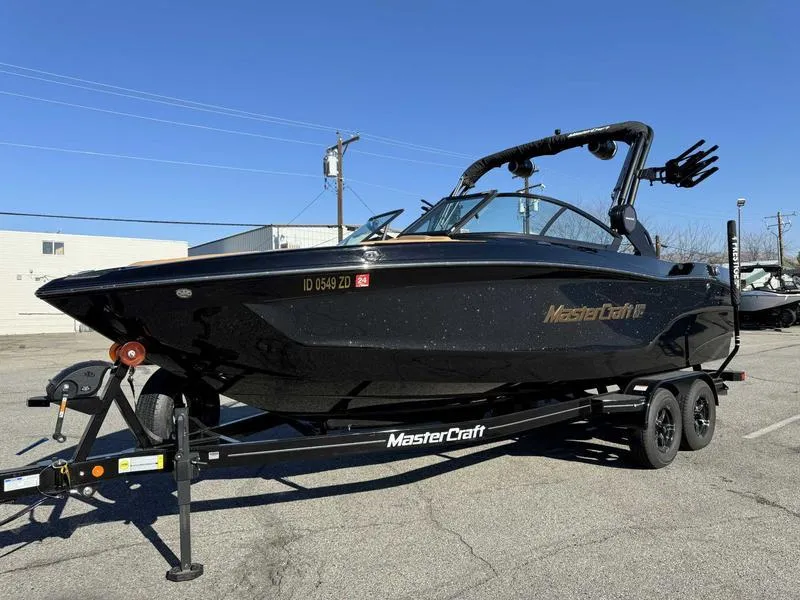 Slide: The Image of 2024 MasterCraft XT23 boat on trailer, sleek black design, parked outdoors. - 2