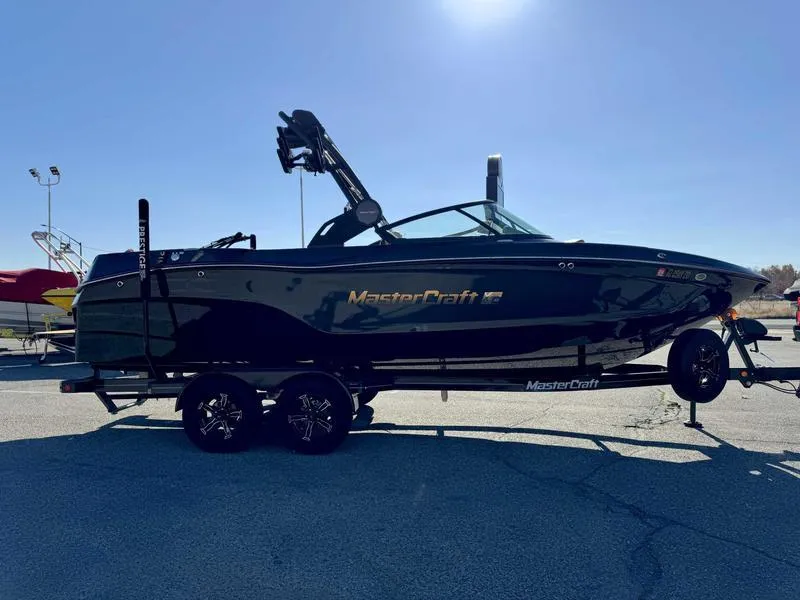 Slide: The Image of 2024 MasterCraft XT23 boat on trailer under clear sky. - 4