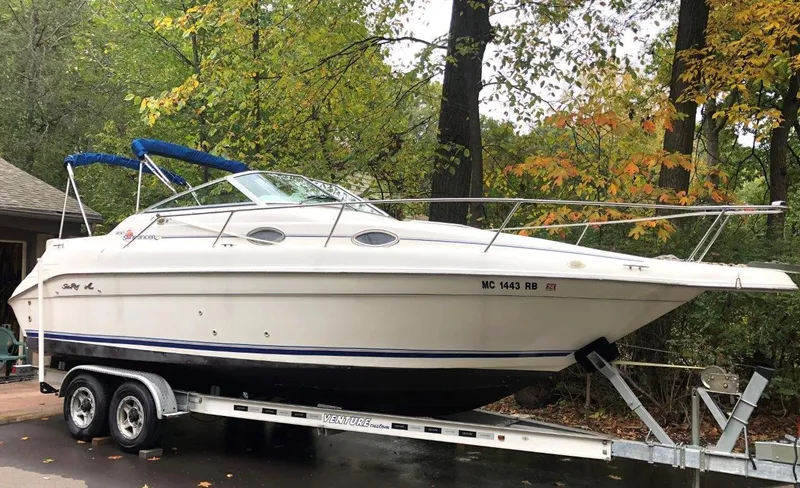 The Image of 1996 Sea Ray 250 Sundancer boat on trailer, surrounded by trees. - 0