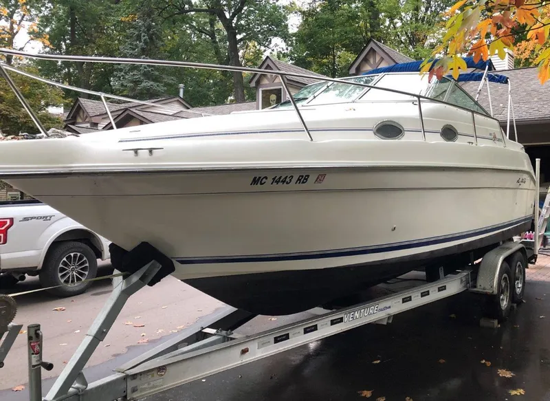 Slide: The Image of 1996 Sea Ray 250 Sundancer boat on trailer, parked outdoors with autumn leaves. - 2