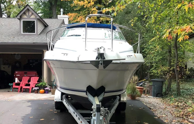 Slide: The Image of 1996 Sea Ray 250 Sundancer boat on trailer in driveway, surrounded by trees and house. - 3