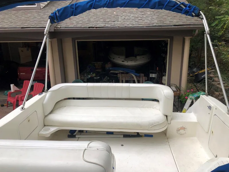 Slide: The Image of 1996 Sea Ray 250 Sundancer boat with white seating and blue canopy in a garage. - 4
