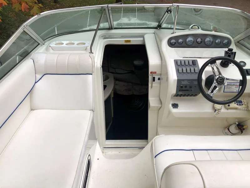 Slide: The Image of 1996 Sea Ray 250 Sundancer boat interior with white seating and control panel. - 5