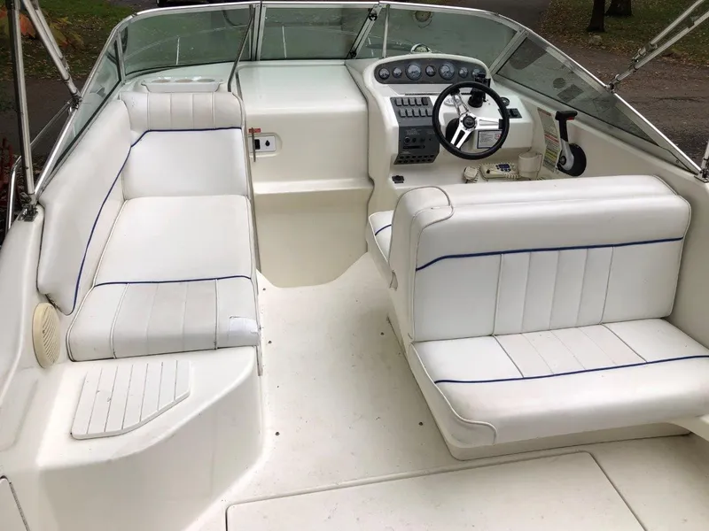 Slide: The Image of 1996 Sea Ray 250 Sundancer boat interior with white seating and steering console. - 6