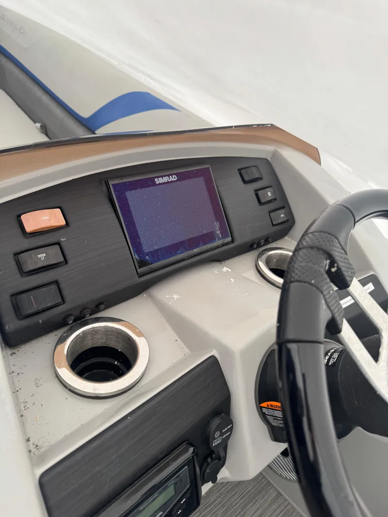 Slide: The Image of 2022 Bennington 23SXSR pontoon boat interior with seating and table on calm water. - 3