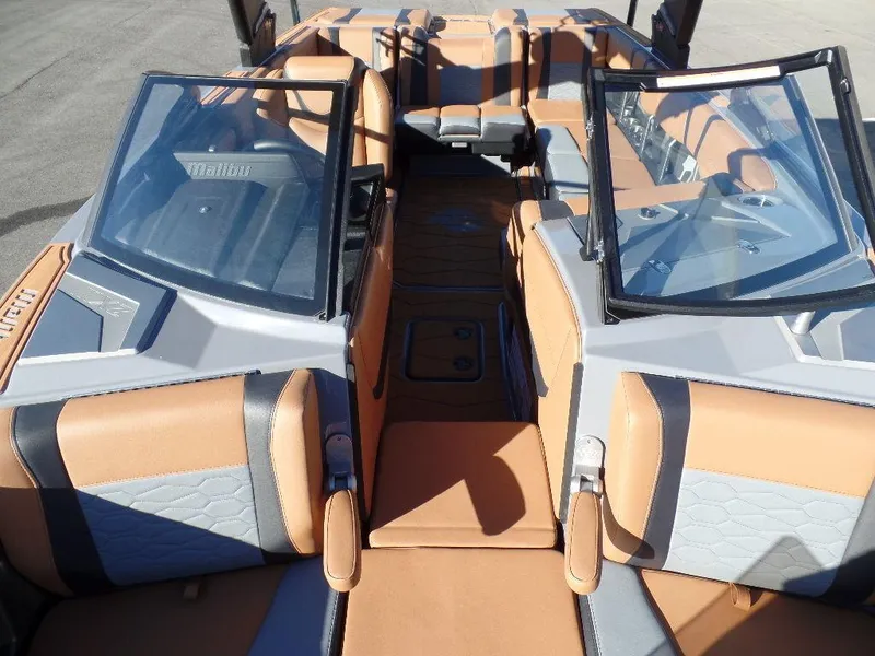 Slide: The Image of 2025 Malibu 23 MXZ boat interior with tan and gray seating, open bow design. - 16