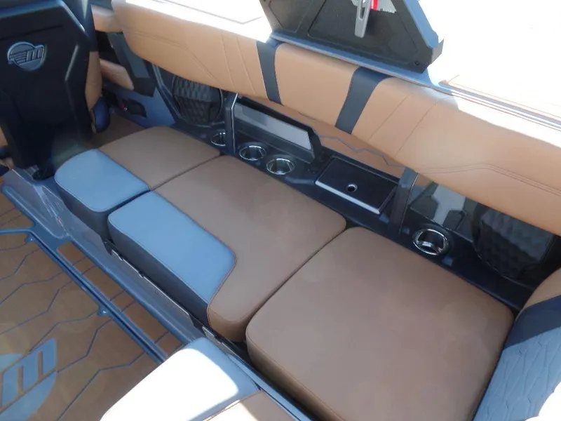 Slide: The Image of 2025 Malibu 23 MXZ interior with tan and gray seating, cup holders, and modern design. - 7