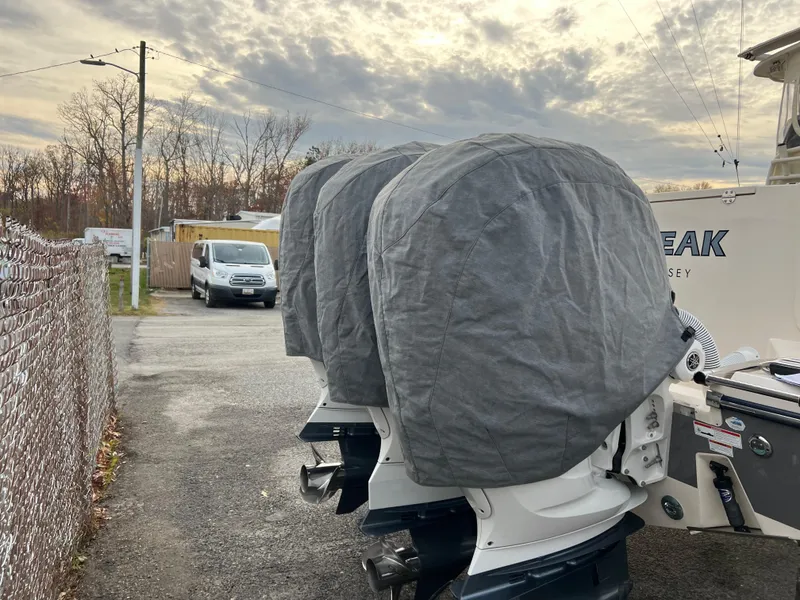 Slide: The Image of 2022 Grady-White Canyon 376 boat engines covered, parked outdoors under cloudy sky. - 13