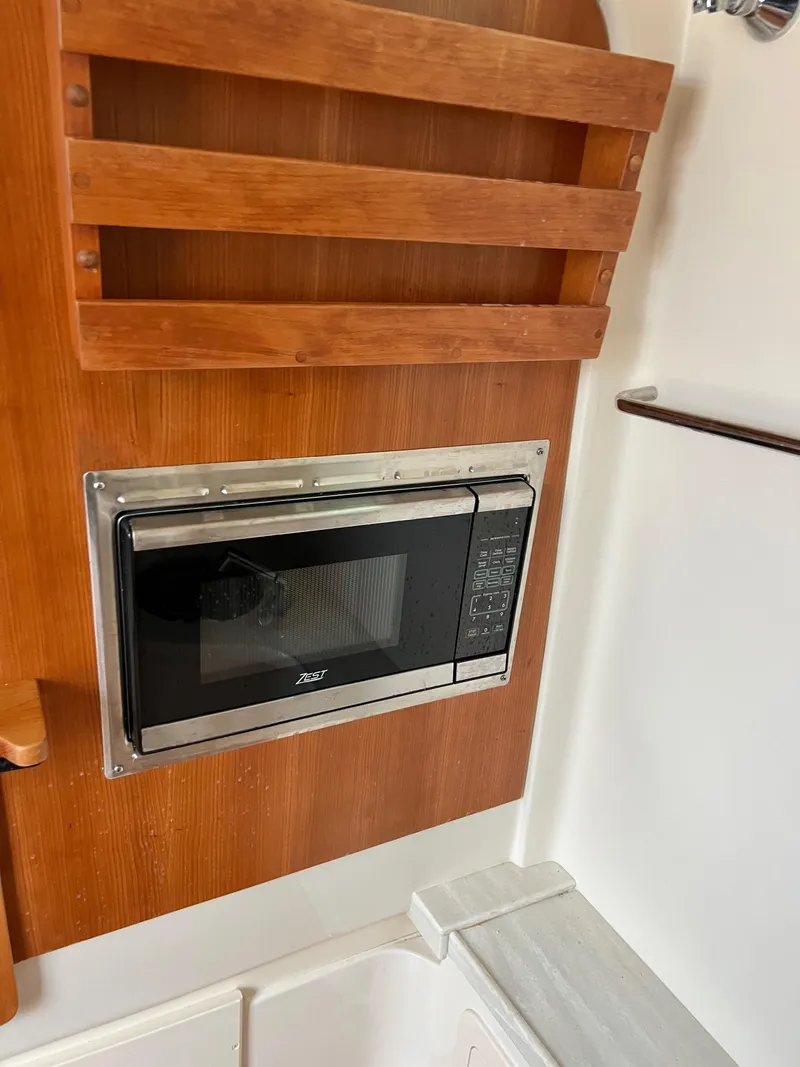 Slide: The Image of 2022 Grady-White Canyon 376 interior with built-in microwave and wooden paneling. - 43