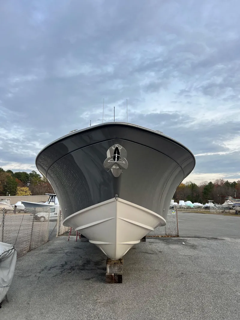 Slide: The Image of 2022 Grady-White Canyon 376 boat on land, viewed from the front under a cloudy sky. - 6