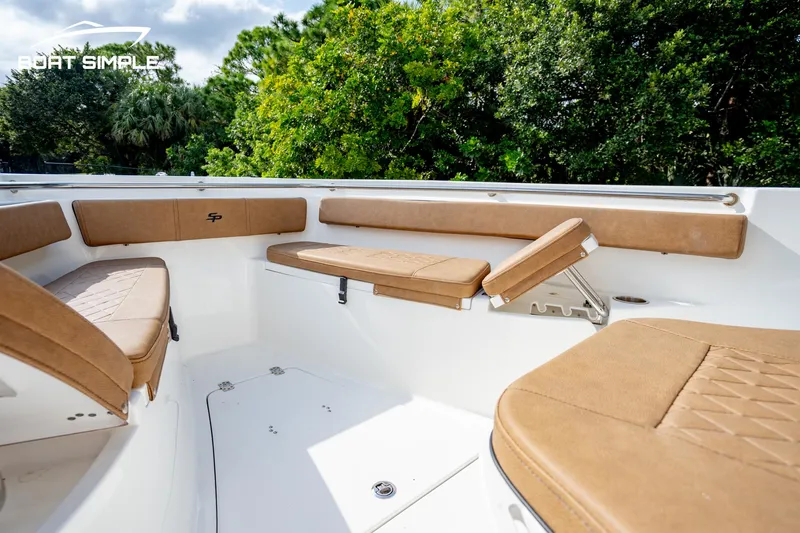 Slide: The Image of 2024 Sea Pro 239 Deep V CC boat interior with tan seating and lush greenery background. - 6