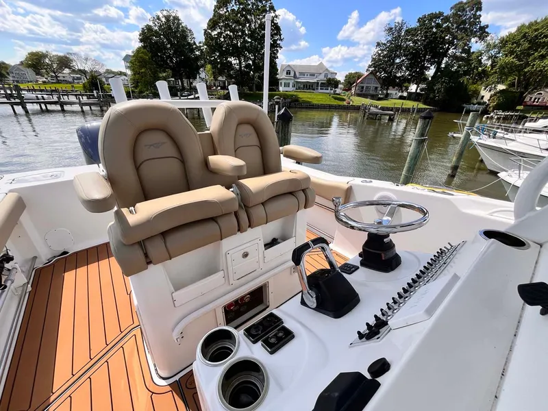 Slide: The Image of 2015 Tidewater 280 CC Adventure boat interior with helm and seating, docked by a scenic waterfront. - 11