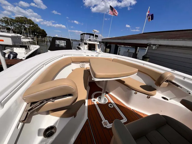 Slide: The Image of 2015 Tidewater 280 CC Adventure boat interior with seating and table, docked under blue sky. - 6
