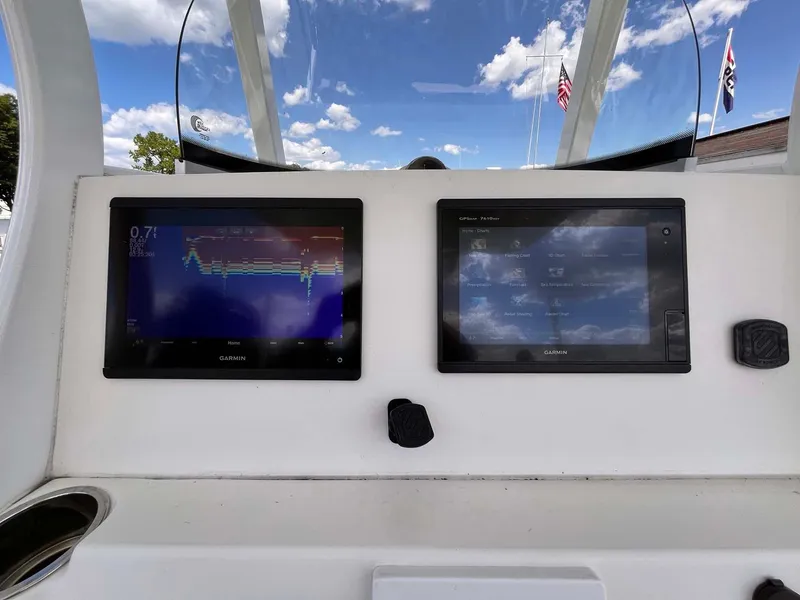 Slide: The Image of 2015 Tidewater 280 CC Adventure dashboard with dual navigation screens under a blue sky. - 8